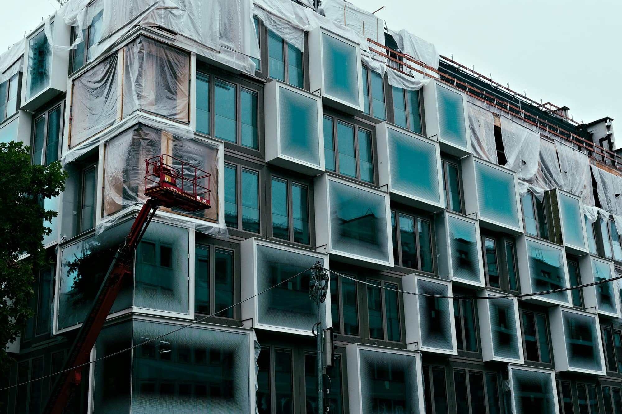 Prédio contemporâneo em fase final de obra, com a fachada de janelas salientes e uma plataforma elevatória