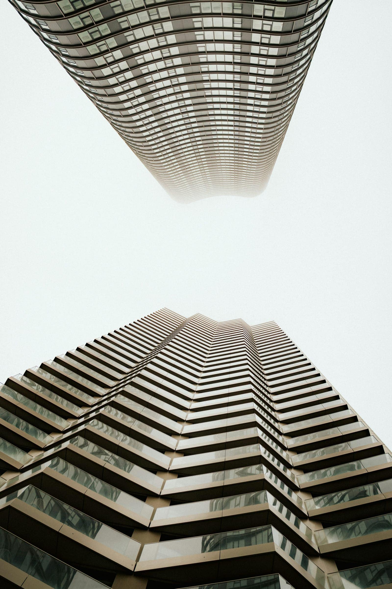 Duas torres de habitação contemporâneas, vistas de baixo, a desaparecer no nevoeiro